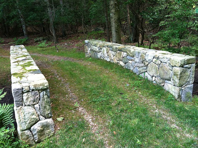 handbuilt stone bridge with grass and dirt path