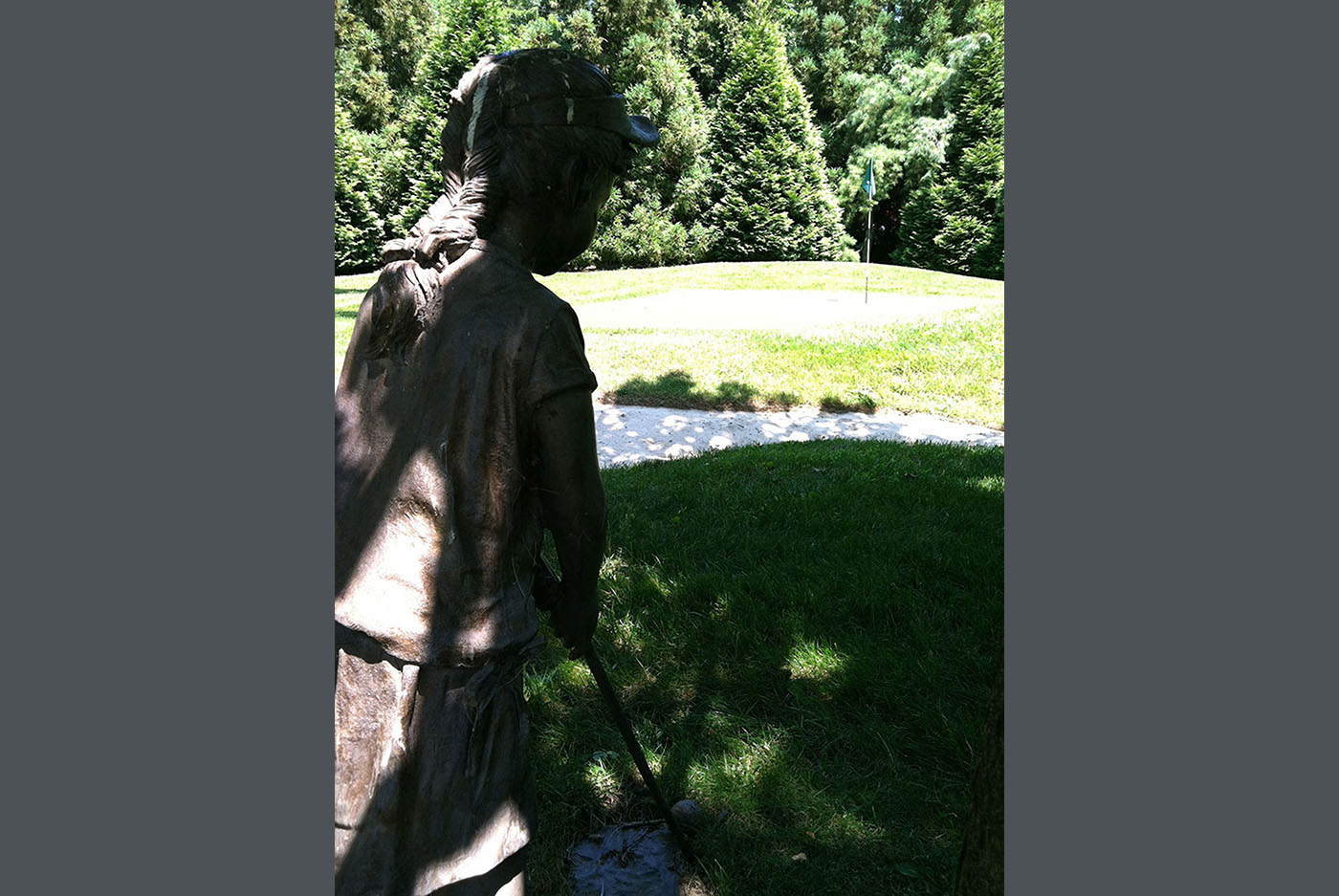 statue of girl in front of putting green