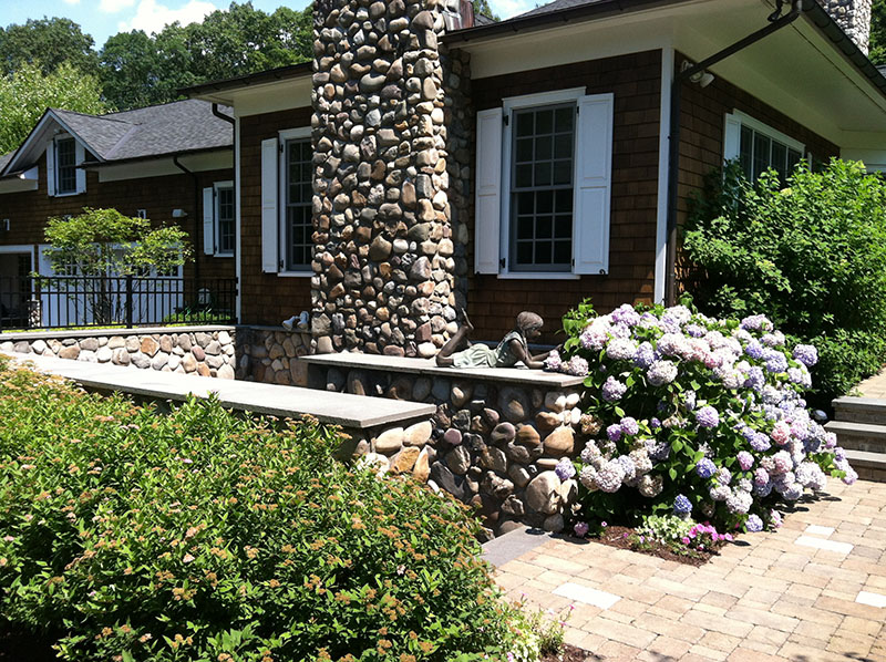 side of house with flowers and statue